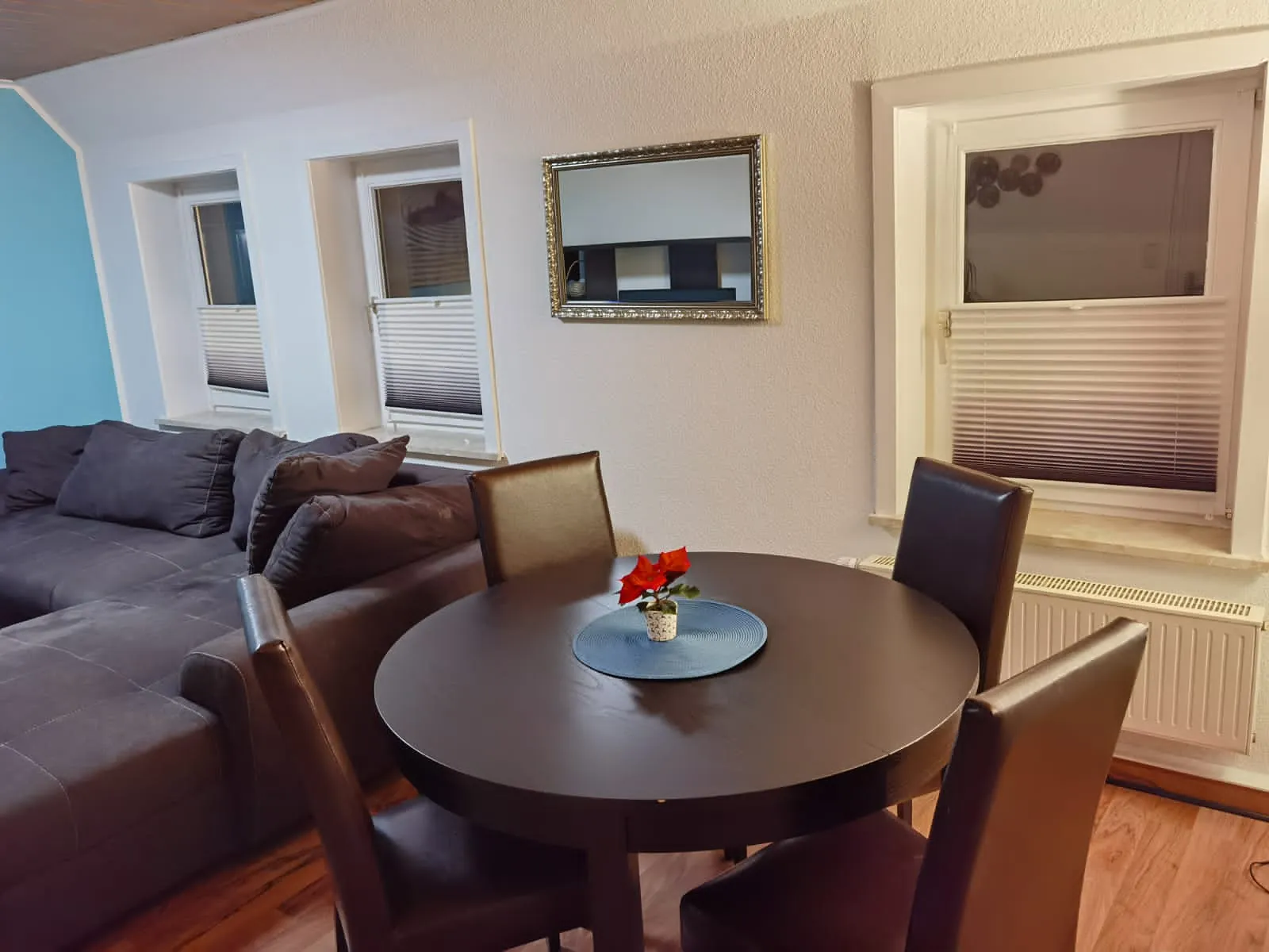 Heller Wohn- und Essbereich der Ferienwohnung in Dransfeld mit Ecksofa, rundem Esstisch und vier Stühlen
